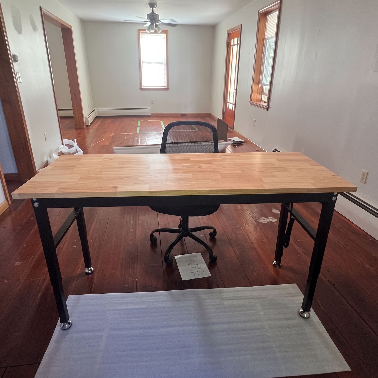 A wood desk with a sewing machine by the window